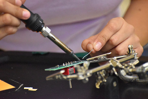 a student practicing soldering a motherboard.
