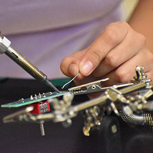 close up picture of a student soldering.