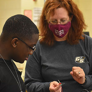 picture of a Georgia Southern Helper assisting a student in the soldering process.